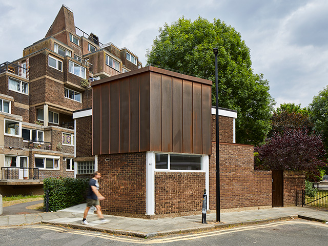 Exterior de la casa de ladrillos y concreto brutalistas en una calle de Londres. La extensión vestida con cobre está en el segundo piso.